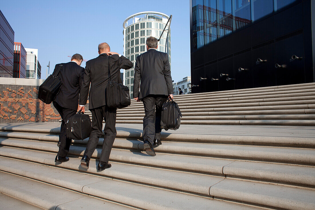 Drei Geschäftsmänner auf einer Treppe zum Informationspavillon der Elbphilharmonie, HafenCity, Hamburg, Deutschland