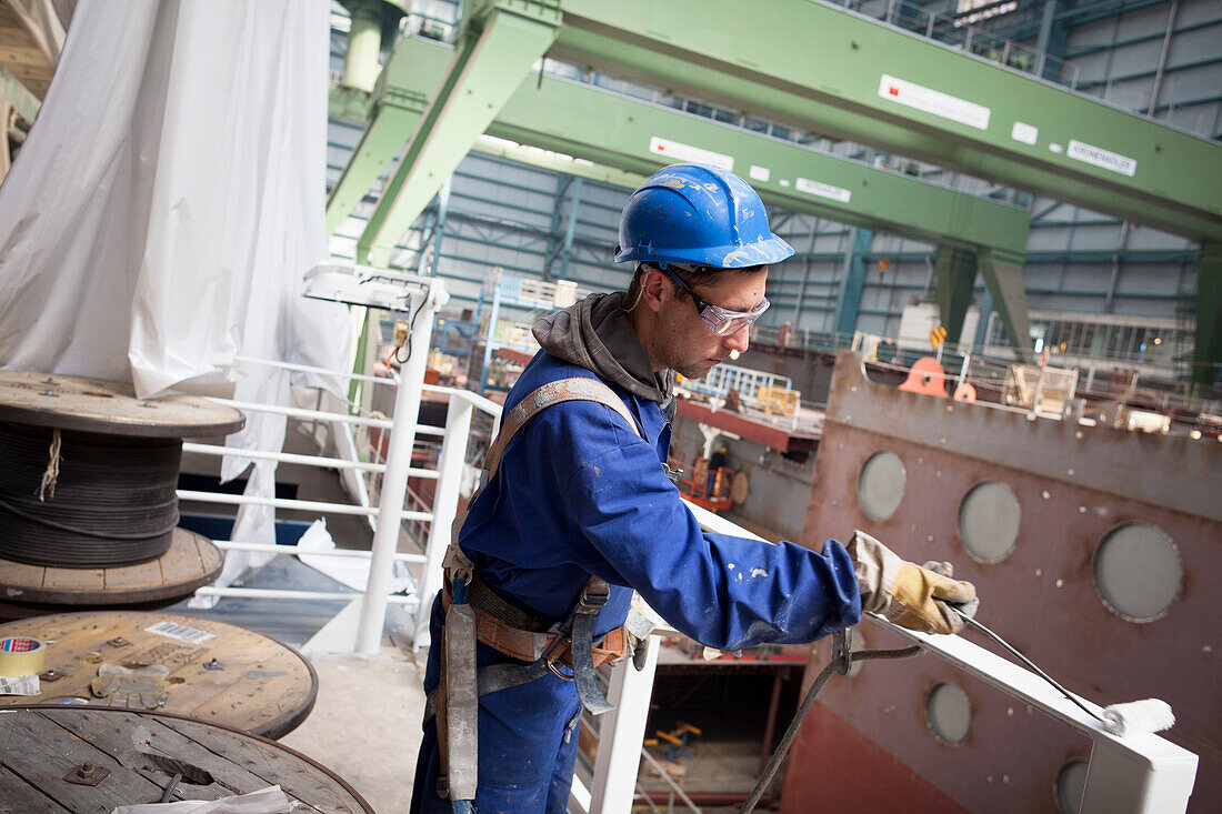 Arbeiter bei Lackierarbeiten an der Reling, Kreuzfahrtschiff im Bau im Trockendock, Meyer Werft, Papenburg, Niedersachsen, Deutschland