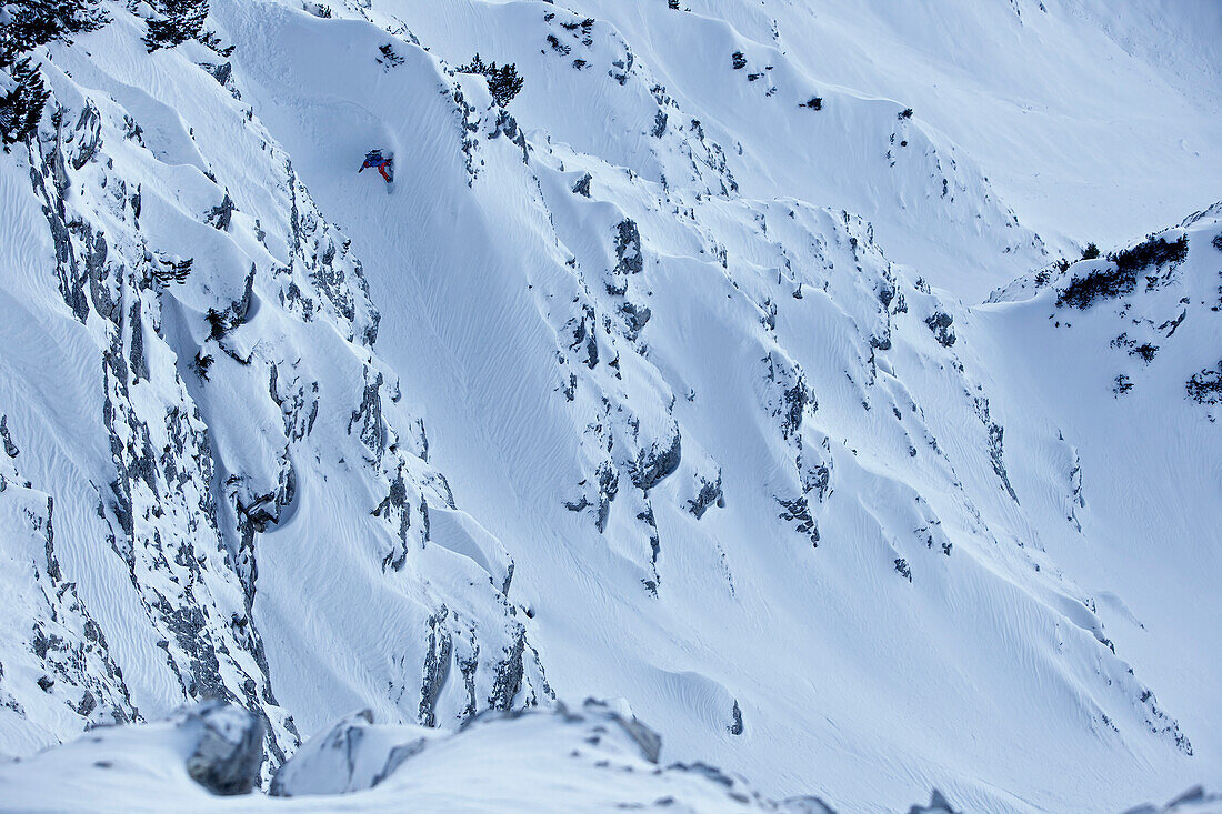 Snowboarder in deep snow between rocks, Oberjoch, Bad Hindelang, Bavaria, Germany