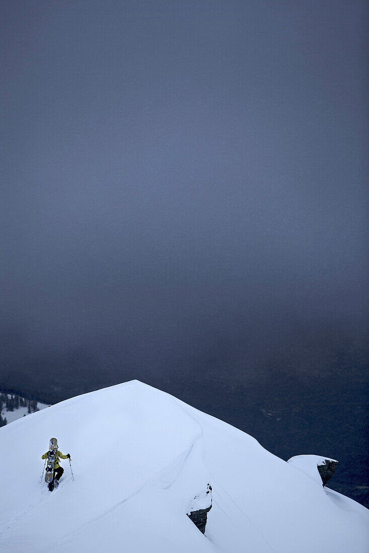 Snowboarder ascending through deep snow, Chandolin, Anniviers, Valais, Switzerland