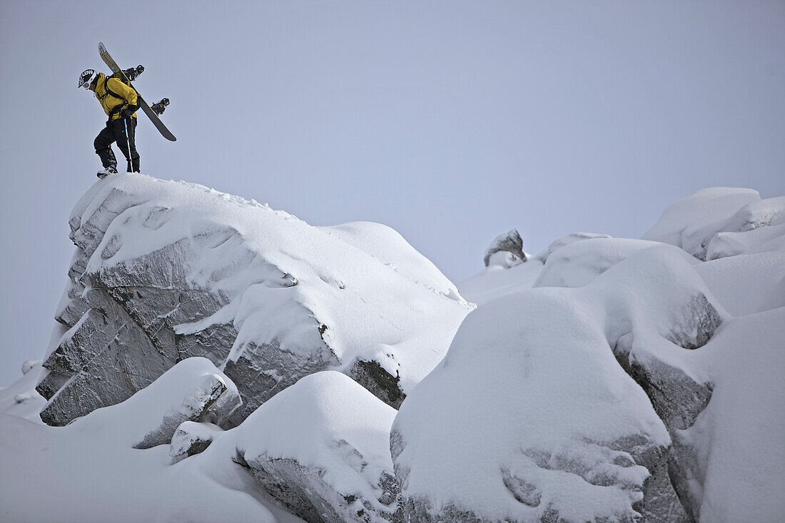 Snowboarder steht auf einem Felsen, Chandolin, Anniviers, Wallis, Schweiz