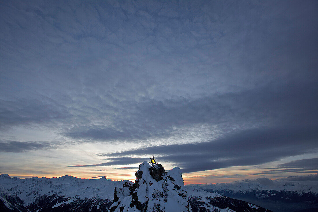 Snowboarder steht auf Berggipfel in der Abenddämmerung, Chandolin, Anniviers, Wallis, Schweiz
