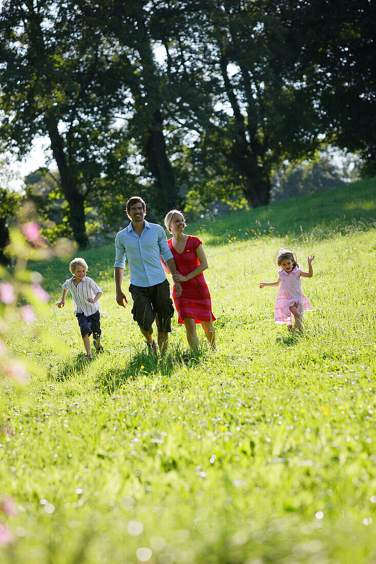 Familie läuft über eine Wiese, Starnberger See, Bayern, Deutschland