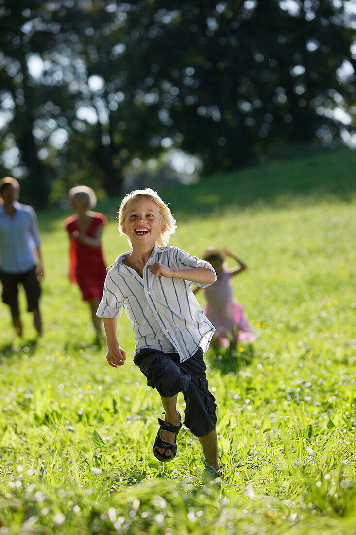 Family walking over meadow, boy in foreground, Lake Starnberg, Bavaria, Germany
