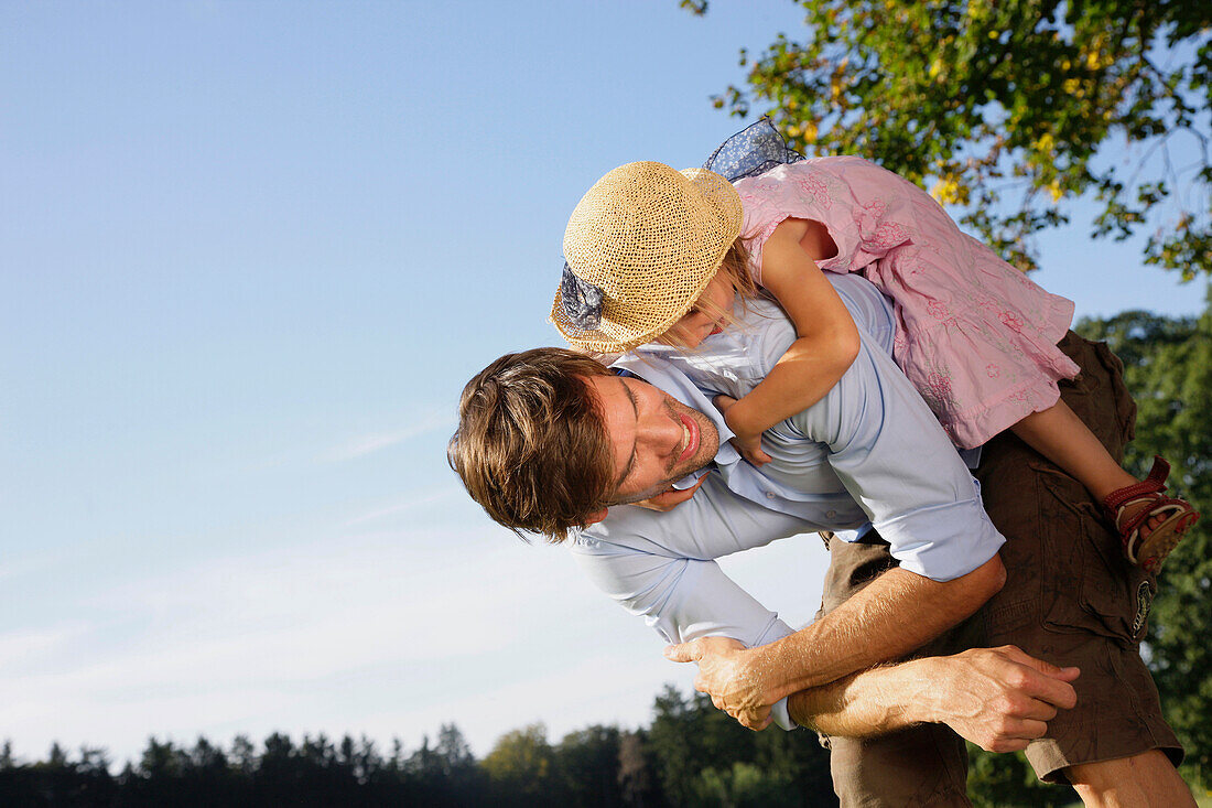 Father giving his daughter a piggyback ride, Lake Starnberg, Bavaria, Germany