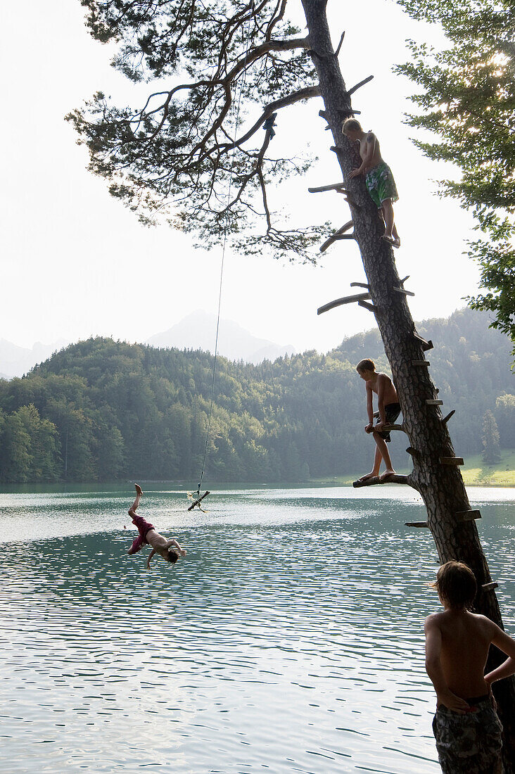 Four boys at lake Alatsee, near Fuessen, Allgaeu, Bavaria, Germany