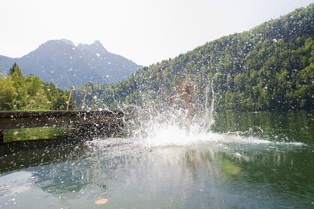 Teenage girl jumping into lake Schwansee, Schwangau, Allgaeu, Bavaria, Germany