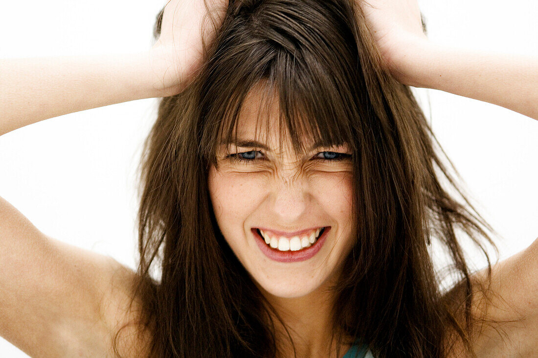 Portrait of a young woman, hands on her brown hair (studio)