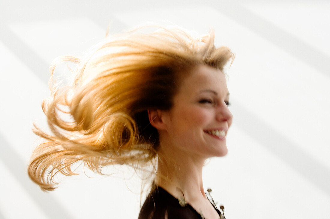 Portrait of a young woman smilng, blond hair, blurred motion