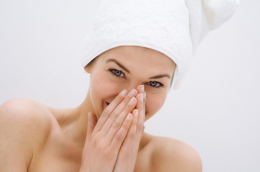 Portrait of a young woman looking at the camera, white hand towel on her head