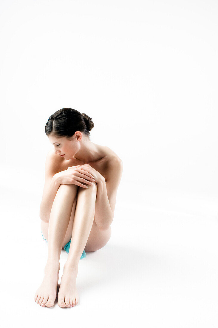 Naked woman sitting on floor (studio)