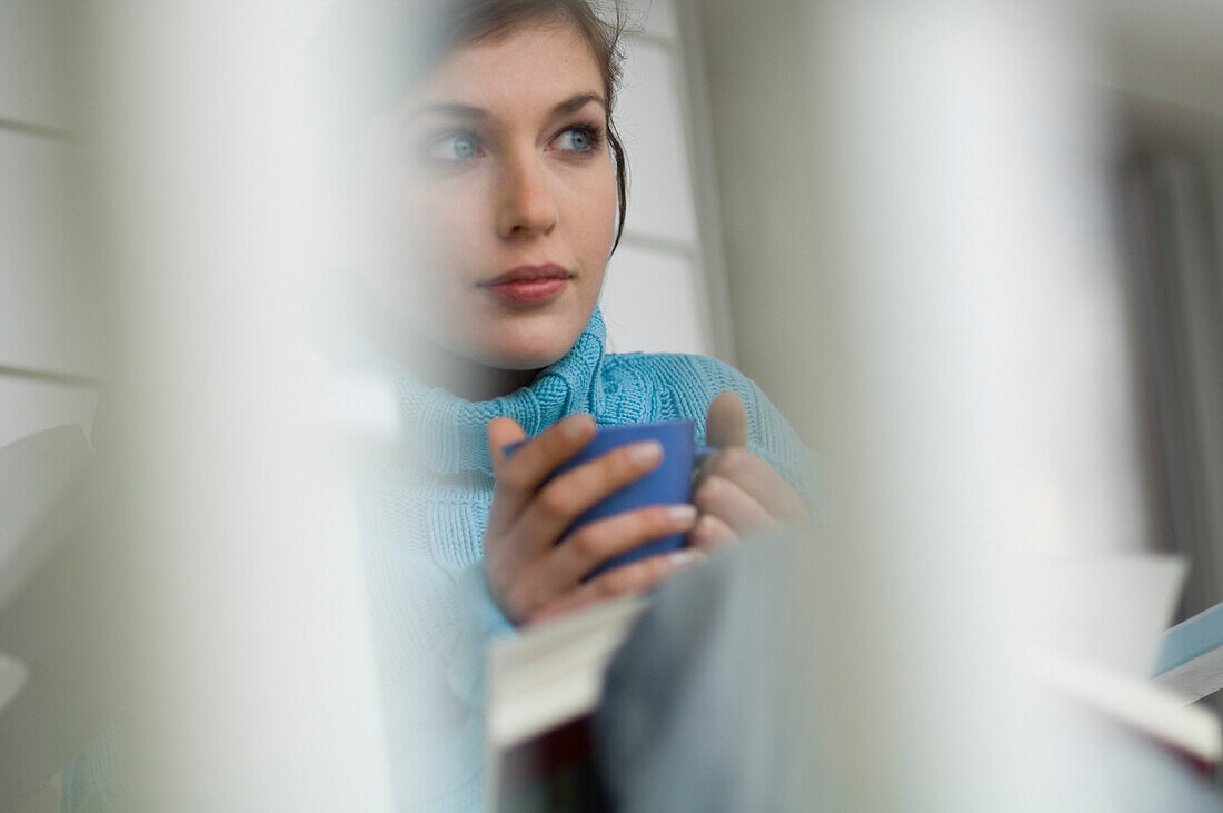 Young thinking woman holding cup
