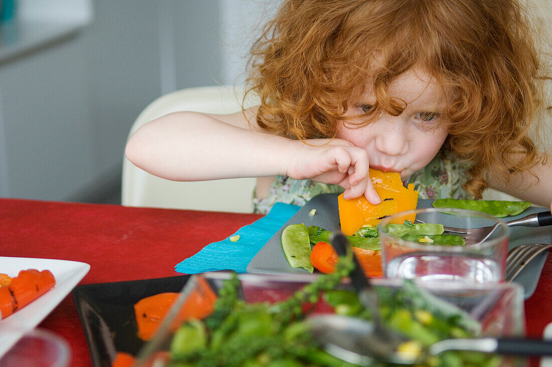 Little girl at lunch table, eating with hands