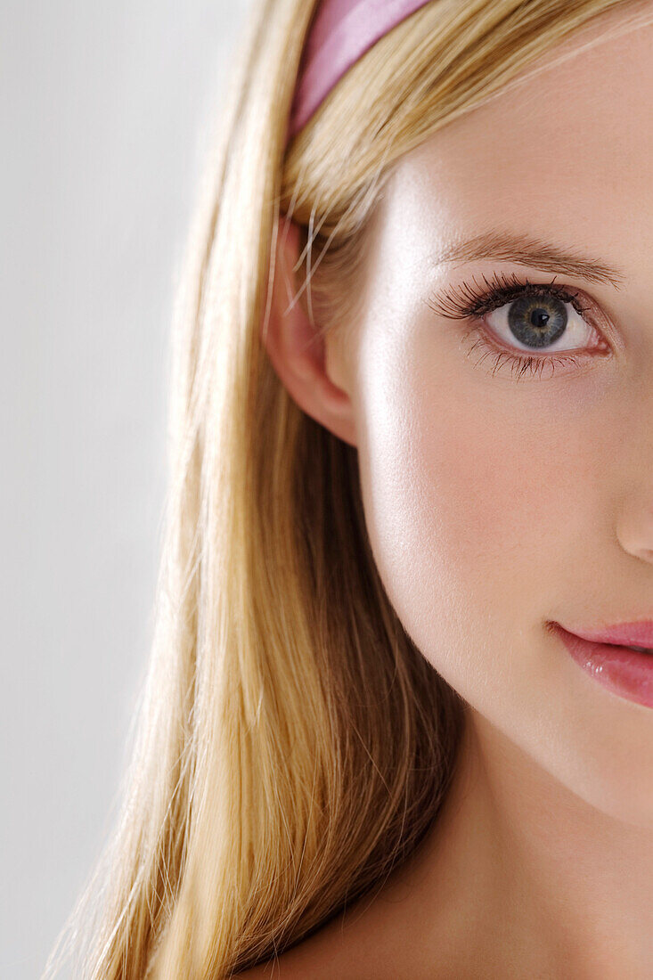 Young Woman half face with make up, looking at the camera, close-up, indoors (studio)