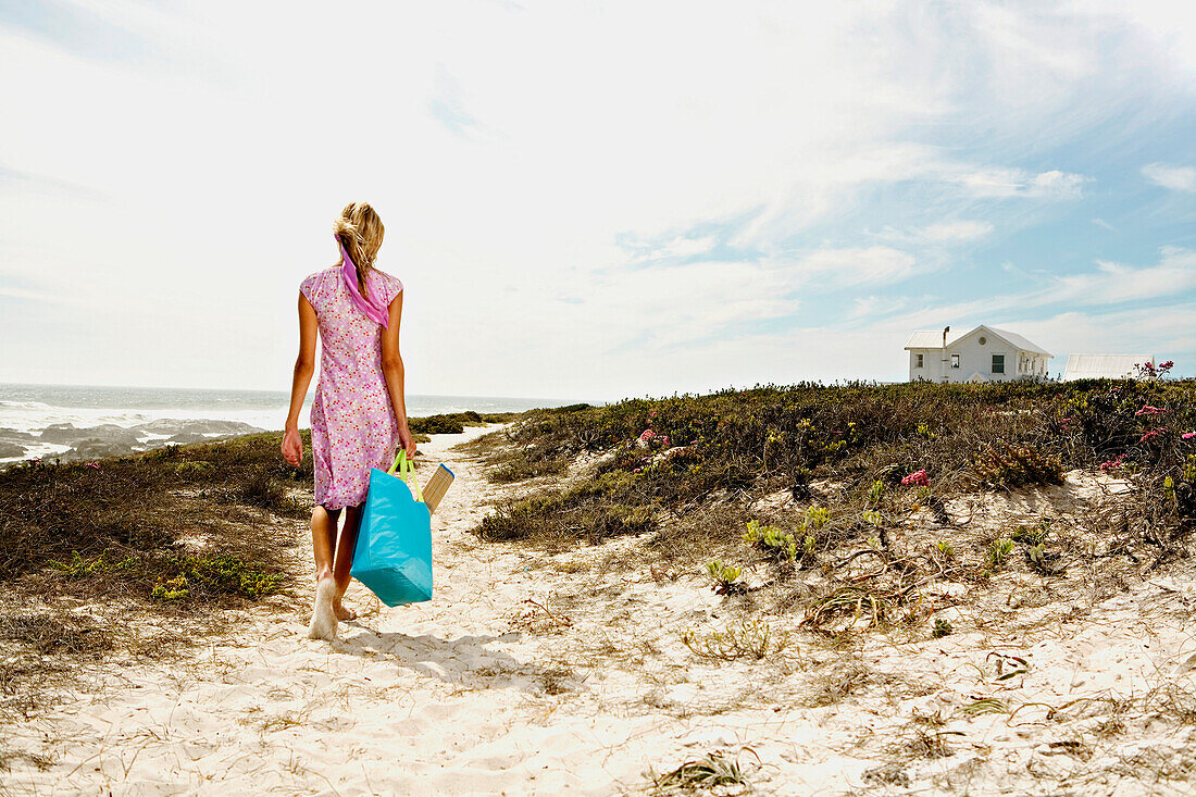 Young woman walking on the beach, rear view