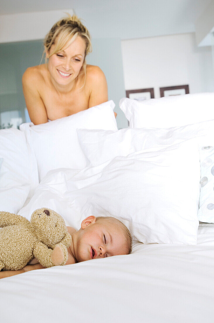 Mother smiling looking at her baby asleep, indoors