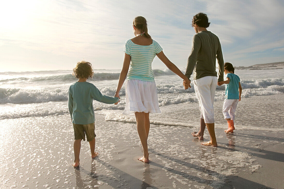 Parents and two children walking on the beach, rear view, outdoors