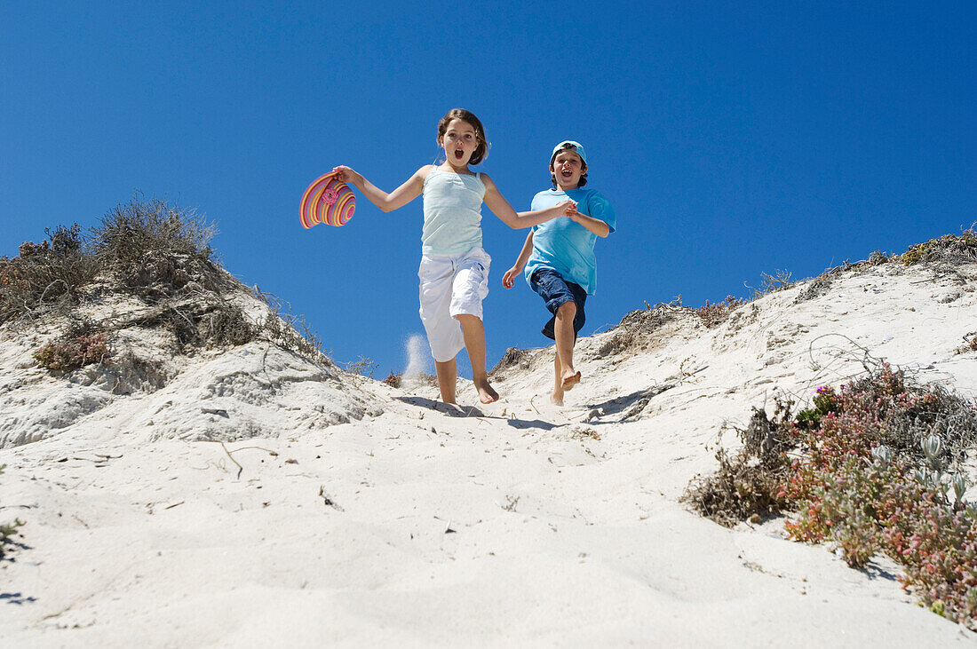 Little girl and little boy running on the beach, outdoors