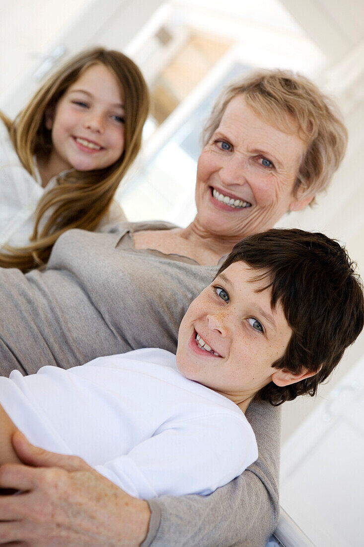 Senior woman and two children smiling for the camera, indoors