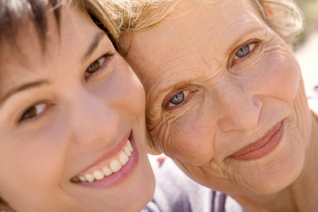 Senior woman and adult daughter smiling for the camera, outdoors