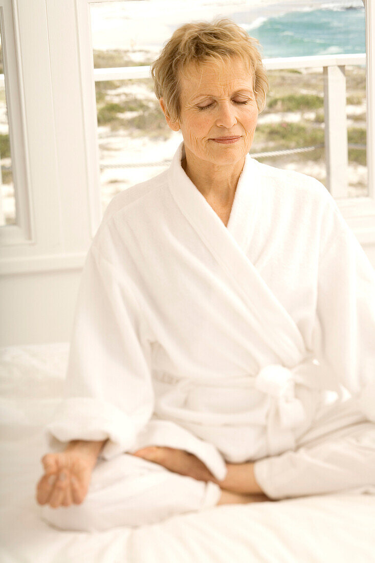 Senior woman sitting cross-legged on bed