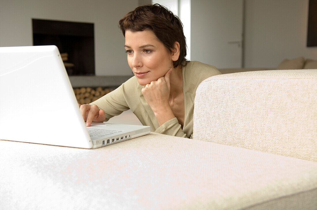 Mid adult woman working on a laptop in a living room