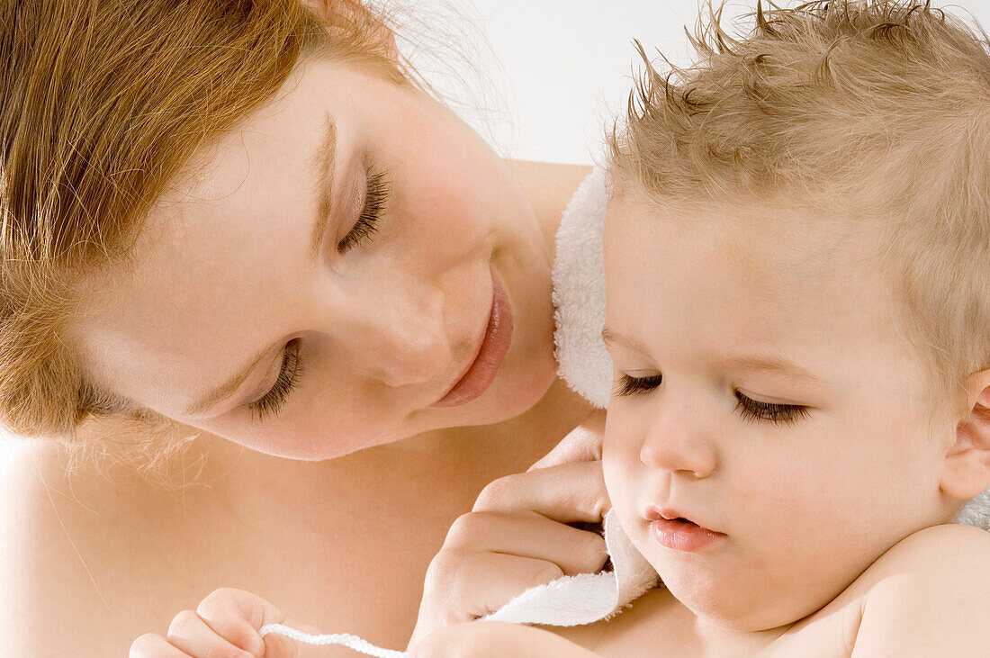 Close-up of a young woman wrapping her son in a towel and smiling