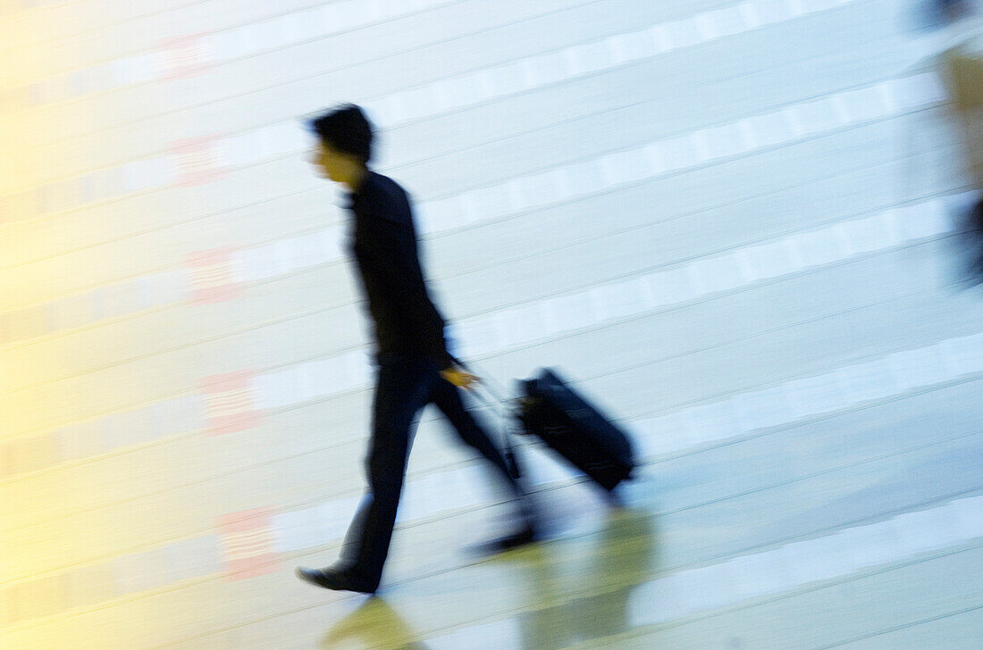 High angle view of a man pulling his luggage at an airport lobby