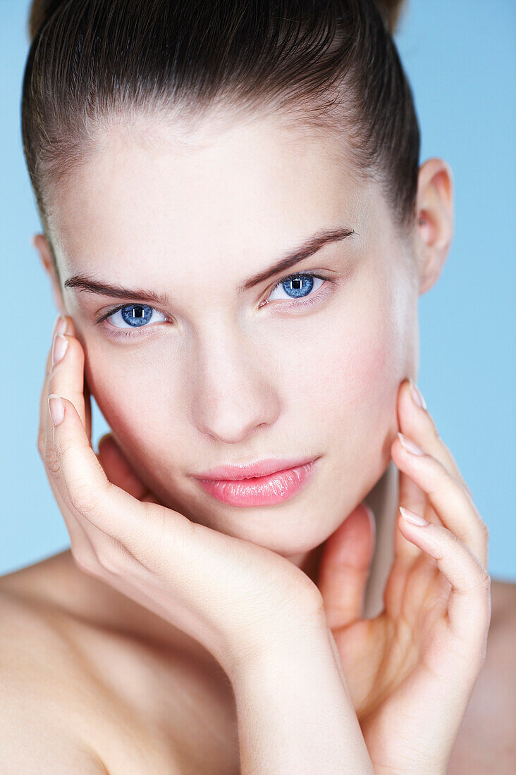 Portrait of young woman with hands on cheeks