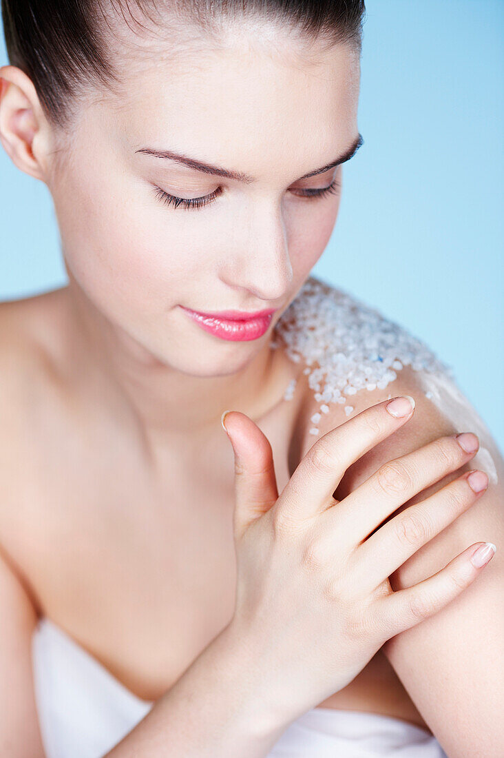 Young woman rubbing her shoulder with salt