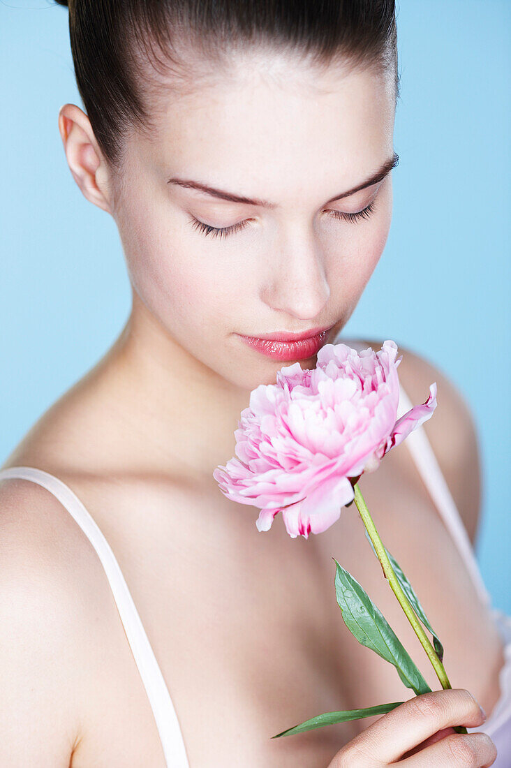 Young woman smelling peony