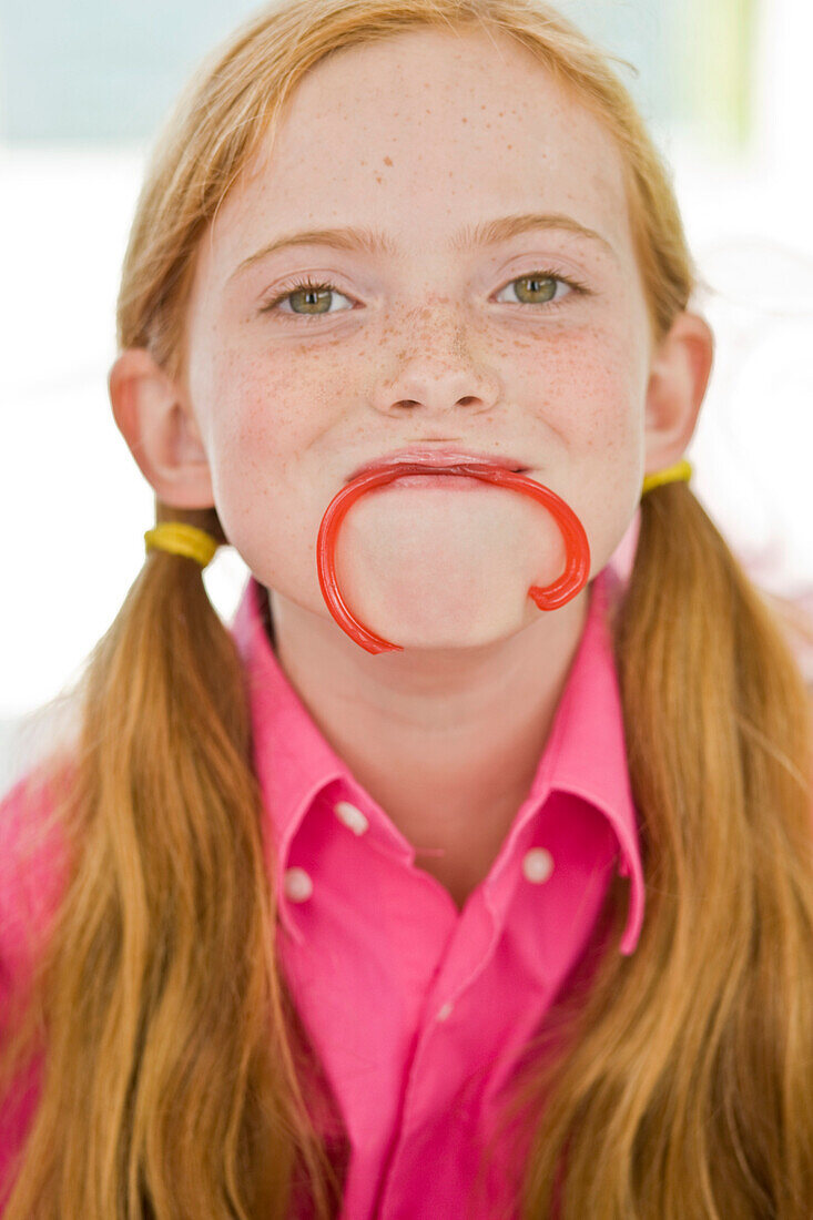 Portrait of a girl holding a candy in her mouth