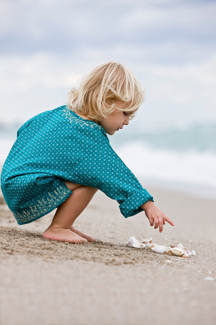Girl playing with shells on the beach