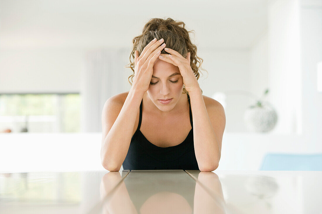 Woman sitting at a table with her head in her hands