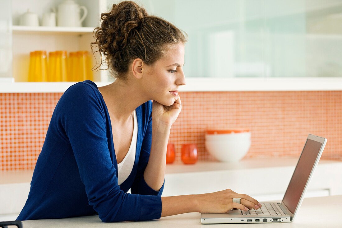 Woman reading a recipe on a laptop in the kitchen