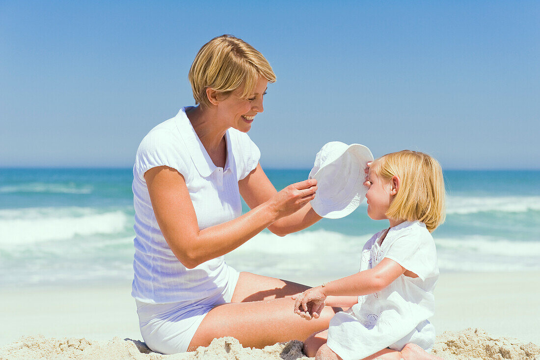 Woman sitting with her daughter on the beach