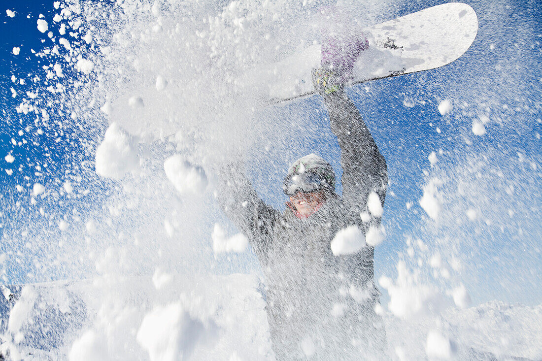 Young man holding his snowboard above his head