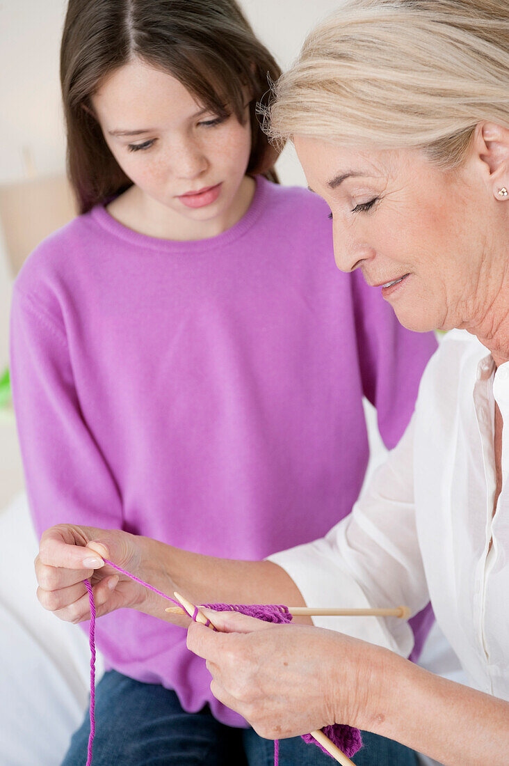 Woman teaching her granddaughter to knit