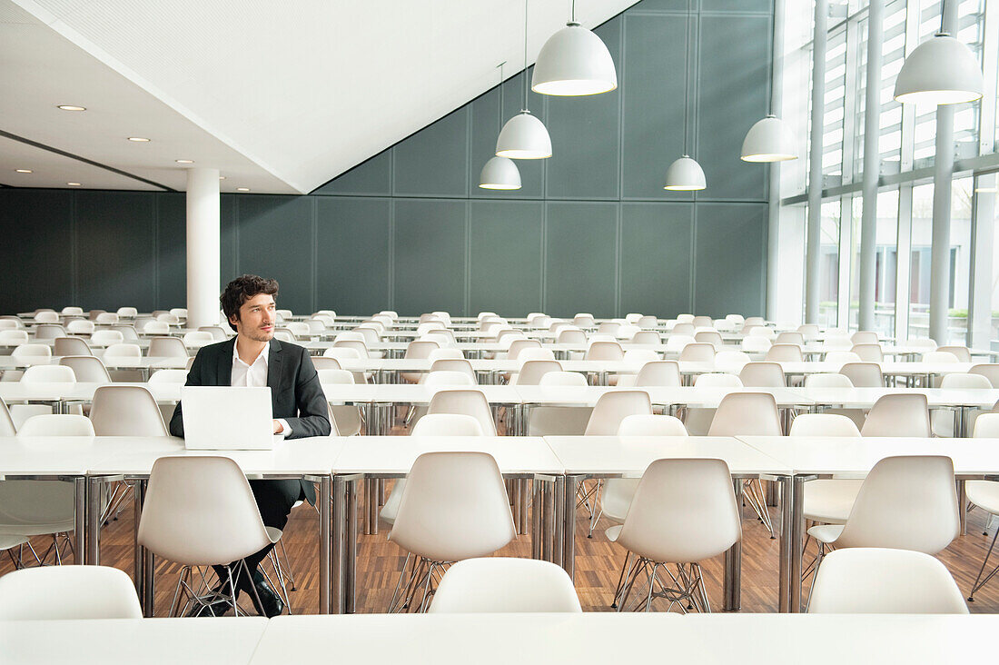 Businessman sitting at a cafeteria and using a laptop