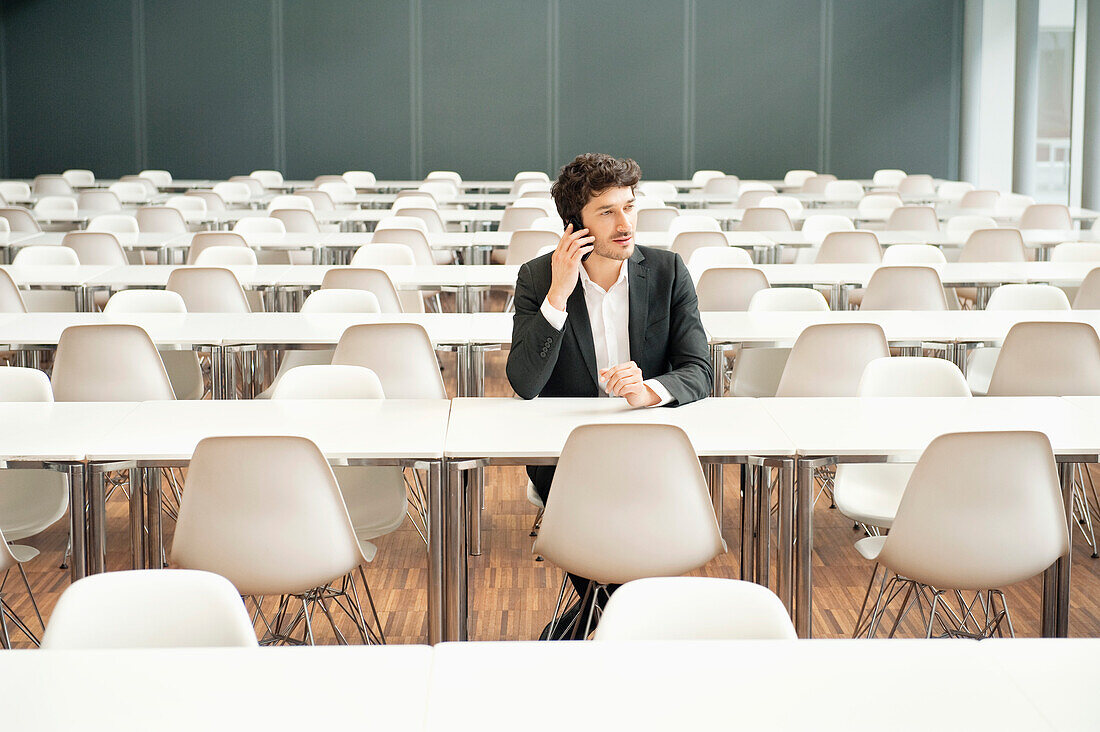 Businessman sitting at a cafeteria and talking on a mobile phone