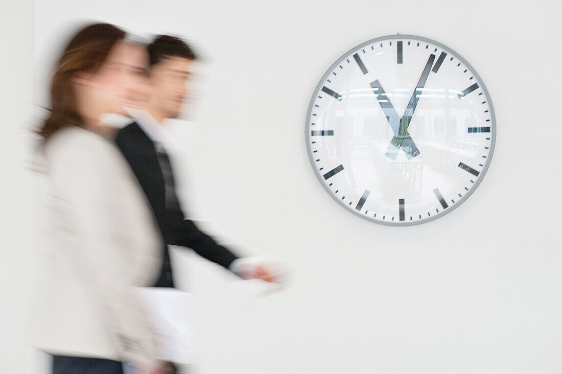 Business executives walking together in front of a wall clock