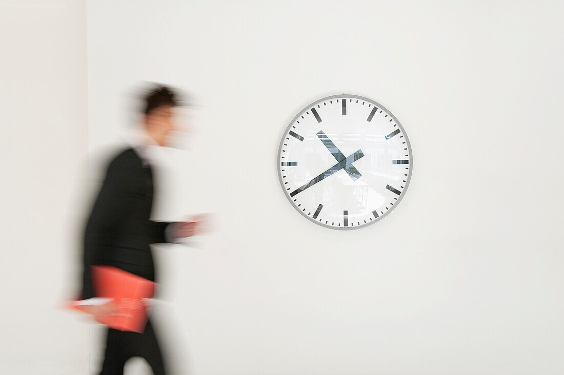 Businessman walking in front of a clock