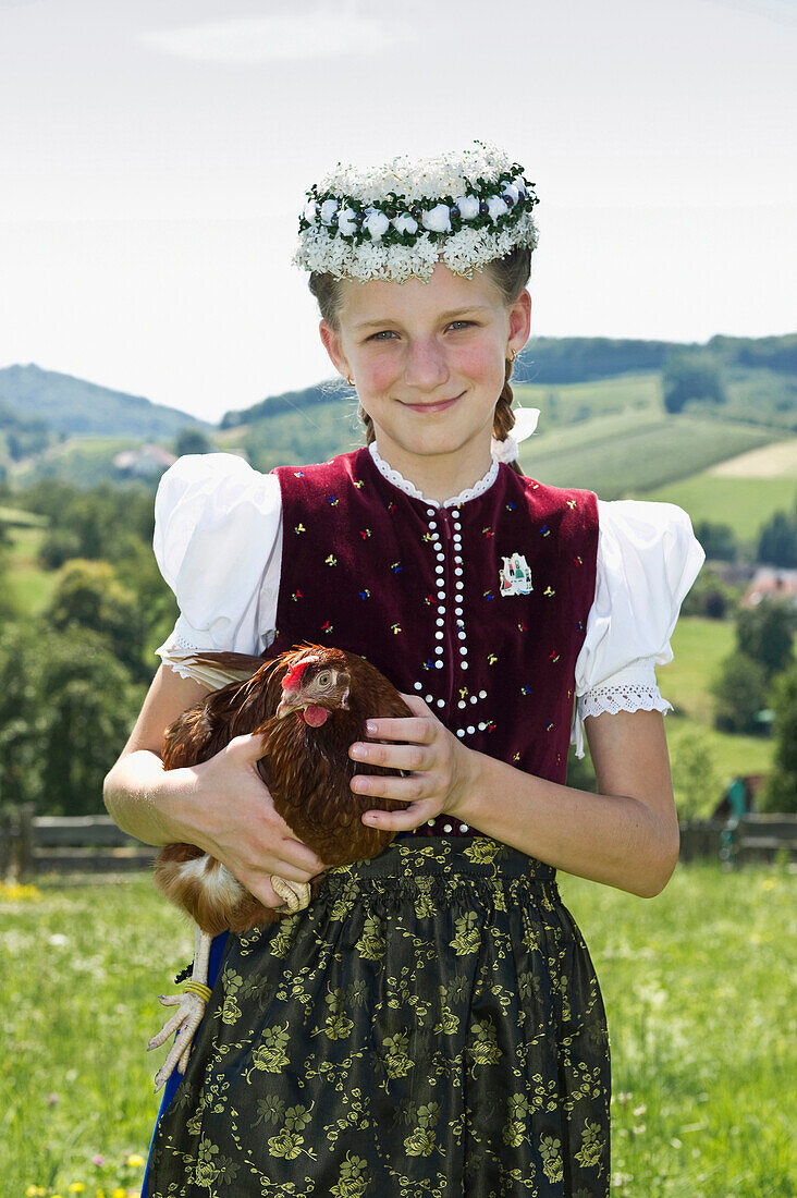 Girl holding an chicken wearing traditional Black Forest clothes, Gottertal, Baden-Wurttemberg, Germany