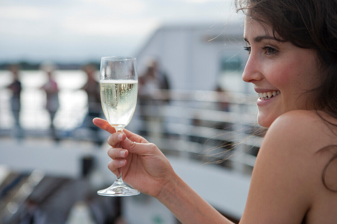 Woman holds champagne glass aboard cruise ship MS Astor (Transocean Kreuzfahrten), MR, Kiel, Schleswig-Holstein, Germany