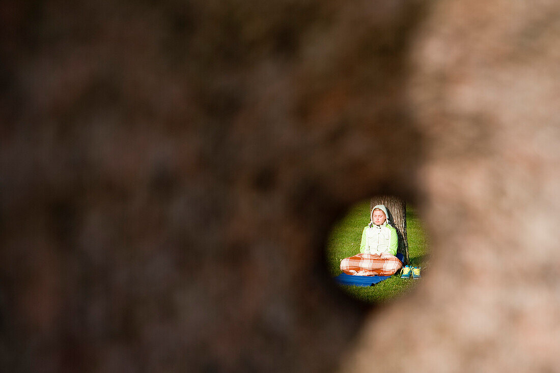Frau meditiert und übt Joga, Blick durch das Loch einer Steinskulptur, Kurische Nehrung, nahe Klaipeda, Litauen, Europa