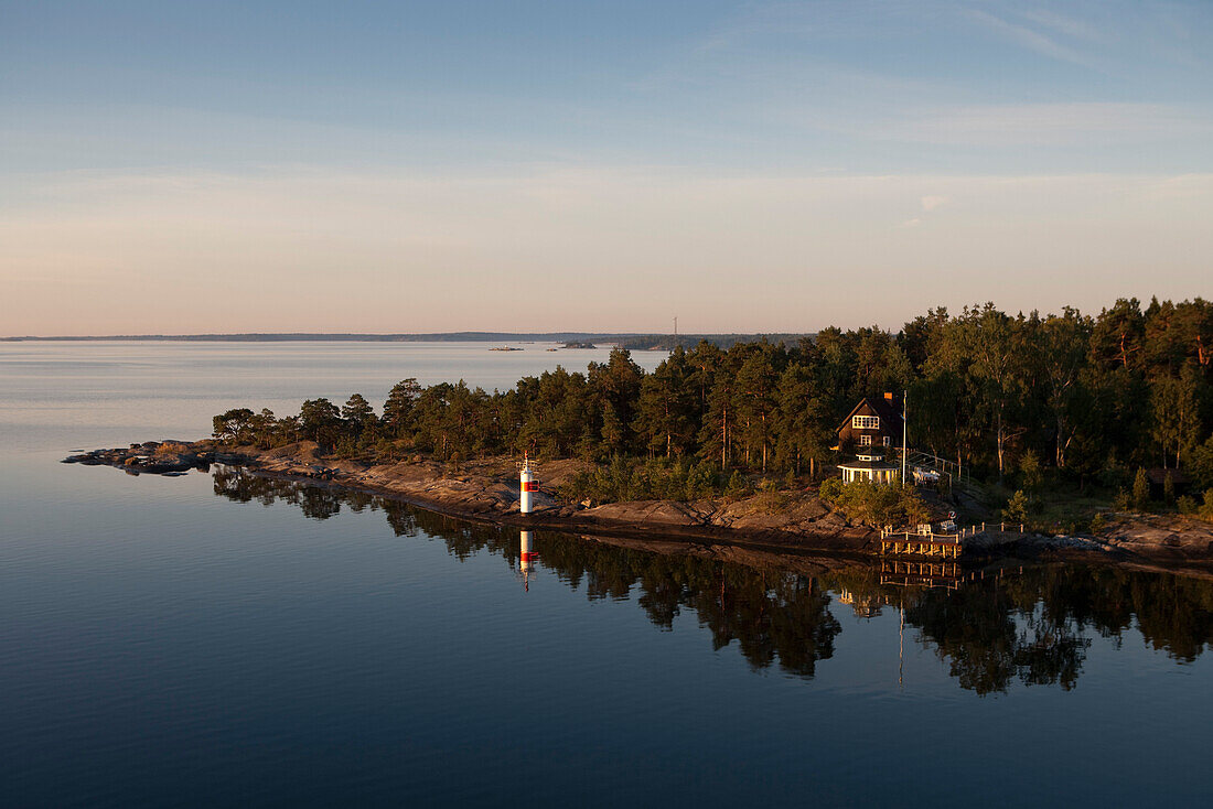 Lighthouse and idyllic house along coastline at entrance to Stockholm archipelago, near Stockholm, Sweden