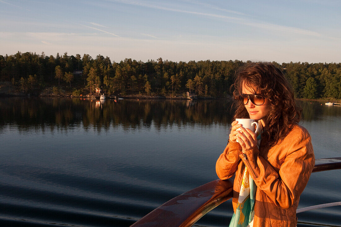 Woman enjoys morning coffee aboard cruise ship MS Astor, Transocean Kreuzfahrten, Stockholm archipelago, near Stockholm, Sweden