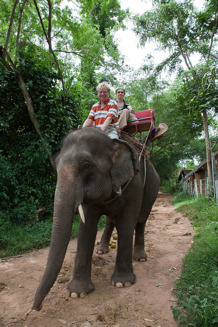 Tourists ride elephants at Sai Yok Elephant Village [MR], near Kanchanaburi, Thailand