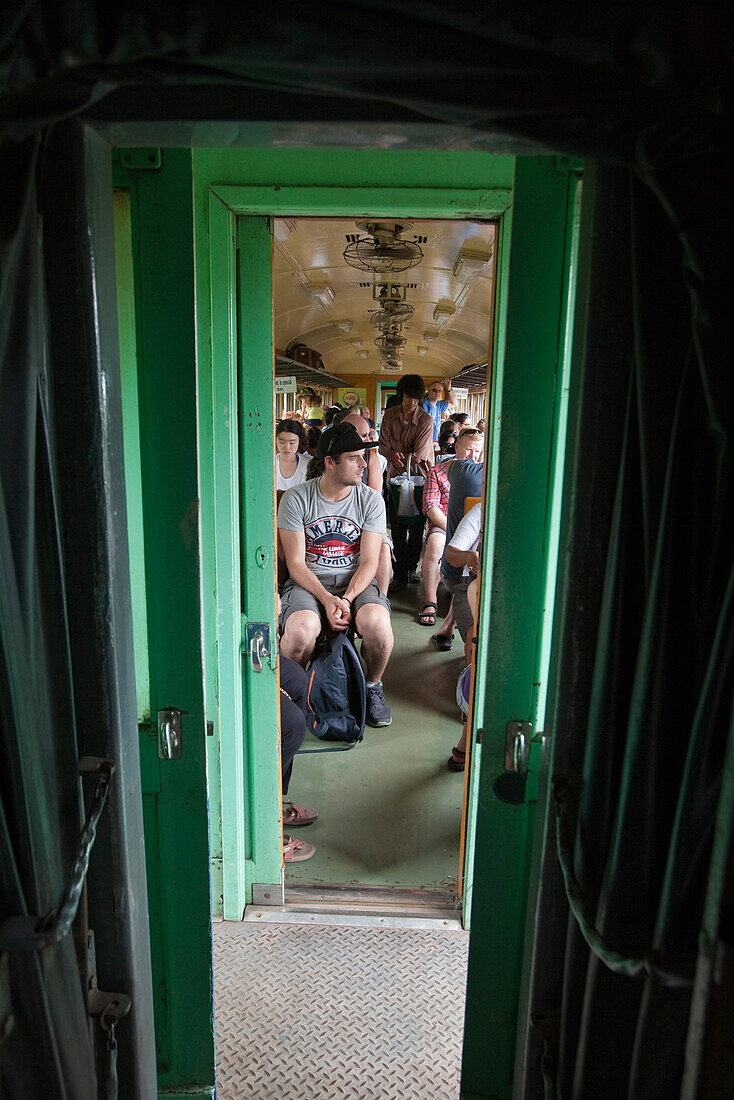 Passagiere in einem Waggon für Touristen auf der Trans-River Kwai Death Railway Eisenbahn entlang dem Fluss River Kwai Noi, nahe Kanchanaburi, Thailand, Asien