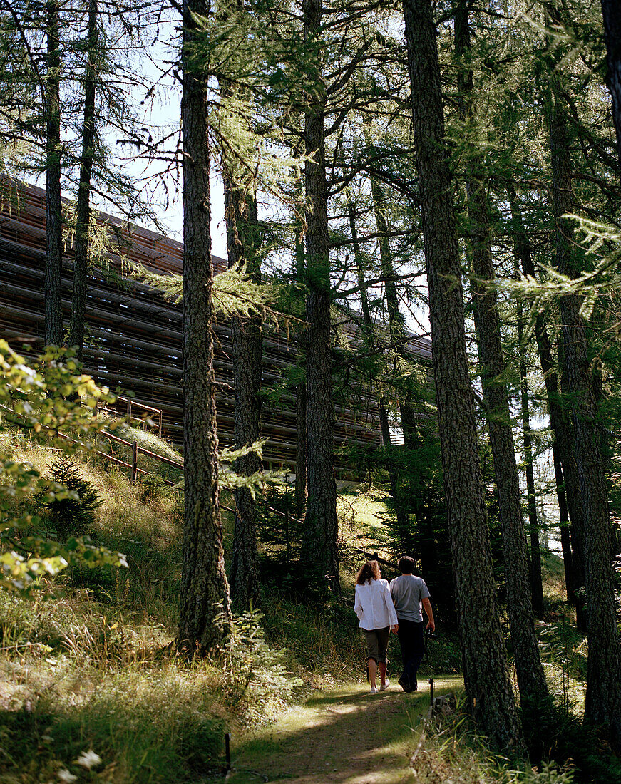 Couple taking a walk through forest, Vigilius Mountain Resort, Vigiljoch, Lana, Trentino-Alto Adige/Suedtirol, Italy